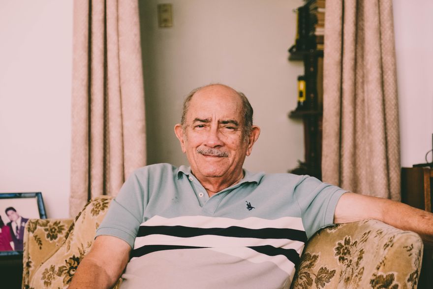 A man in his eighties sitting comfortably in his armchair at home